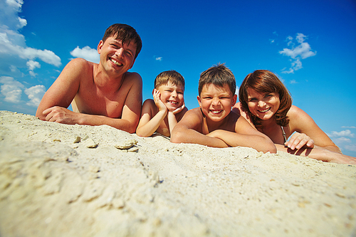 Happy family lying on sandy beach and 