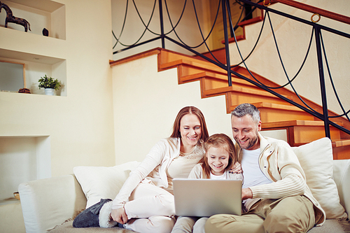 Happy family sitting at home and spending evening with laptop