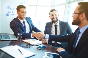 Happy businessmen handshaking after negotiation in office