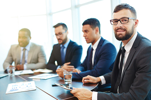 Happy businessman  at conference with colleagues on background