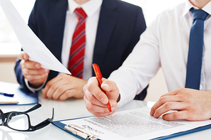 Businessman with pen over contract reading it