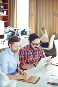 Two male employees planning work at meeting