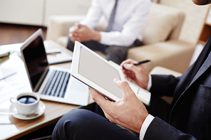 Male employee with touchpad working with data on background of colleague