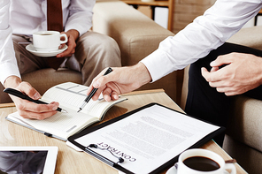 Businessman pointing at note in his partner notepad during discussion