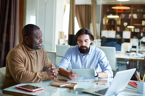 Young businessman with touchpad and his colleague learning new data