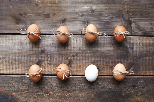 Two rows of eggs tied by threads on wooden background