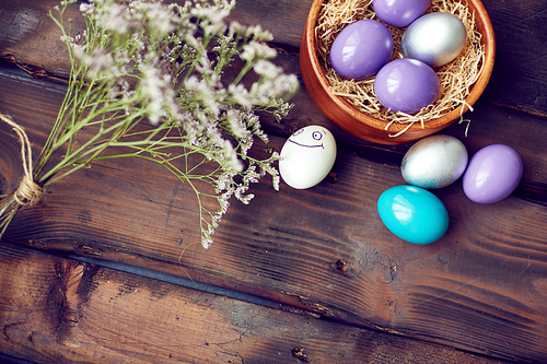 Colorful Easter eggs and dry flowers on wooden background