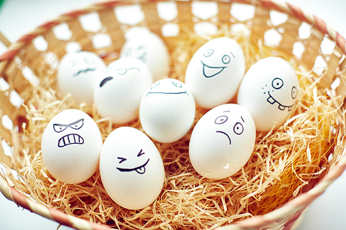Basket with funny eggs with painted faces expressing different emotions