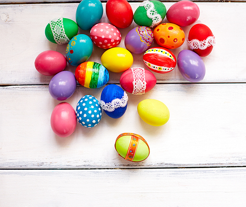 Creatively painted Easter eggs on white wooden background