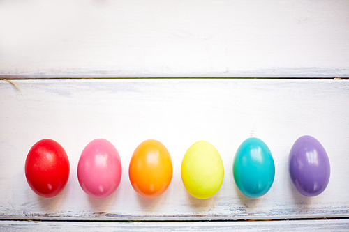 Row of painted Easter eggs on white wooden background