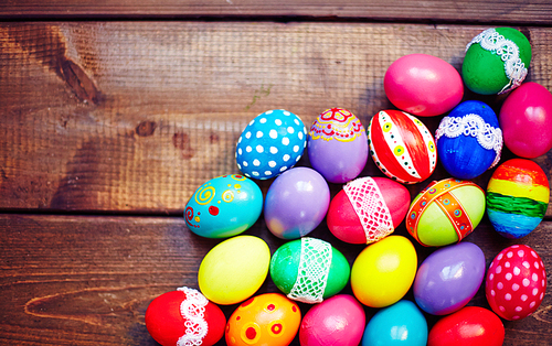Creative Easter eggs of different colors on wooden background