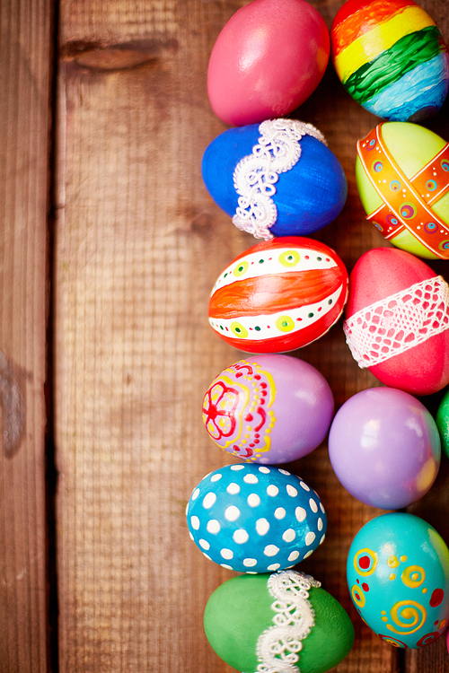 Two rows of painted eggs on wooden background
