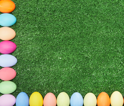 Two crossing lines of painted eggs making corner on green grass