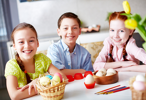 Group of children sitting at table with eggs