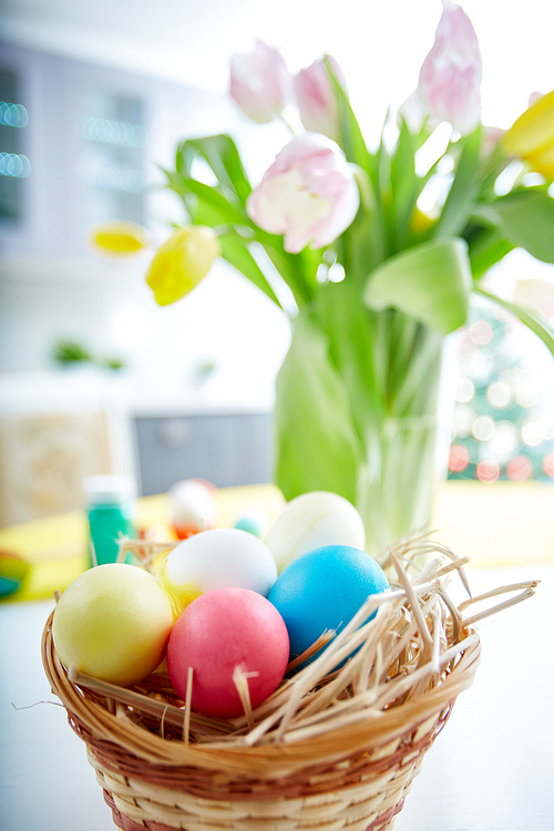 Easter symbols in basket with fresh tulips on background