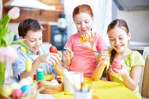 Three children decorating Easter eggs