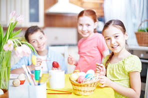 Portrait of happy girl  while painting egg on background of her friends