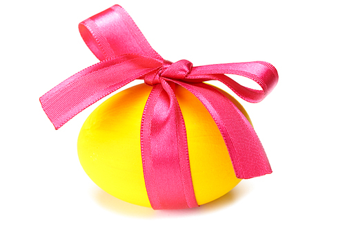 Close-up of yellow Easter egg tied up by pink ribbon