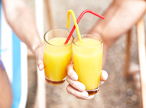 Glasses with orange juice held by couple