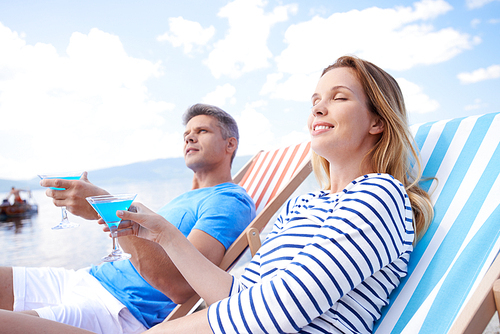 Young man and woman with martini relaxing at summer resort