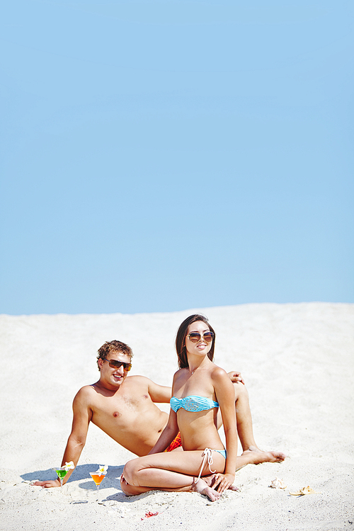 Young couple sunbathing on sandy beach