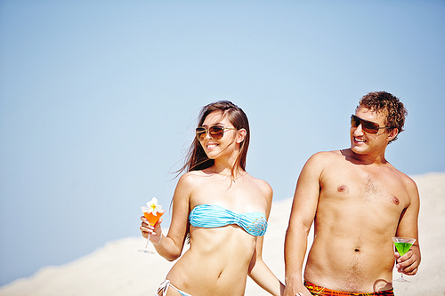 Young couple with cocktails having beach party