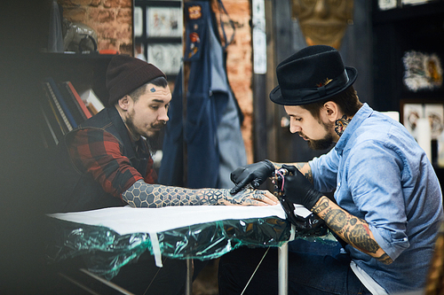 Master of tattooing and his client in salon