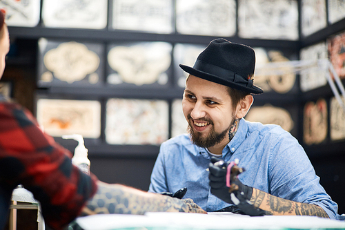Happy master of tattooing and his customer talking in salon