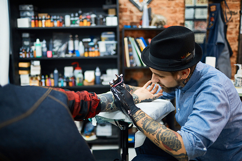 Tattooist drawing tattoo on skin of his client