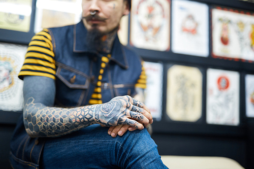 Man with tattooed arms sitting in salon