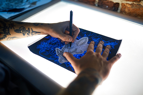 Hands of tattooer drawing picture of new creative adorment