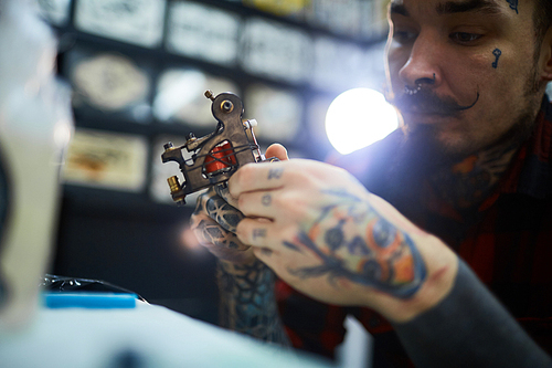 Tattoo-machine in hands of master