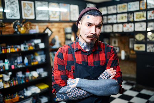 Young bearded hipster with tattooes on arms and face 