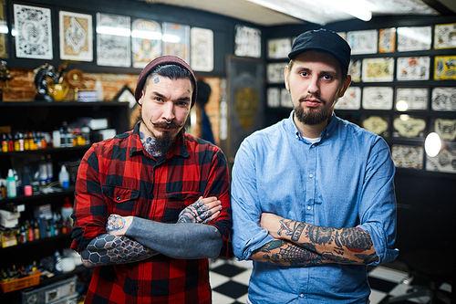 Stylish guys with crossed arms  in tattoo salon
