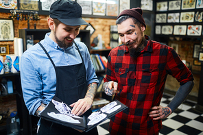 Master of tattoo helping his client to choose ornament