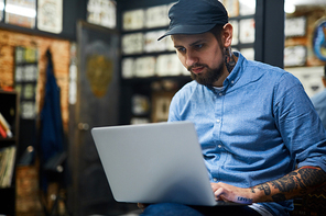 Stylish young man searching for new creative ideas for tattoo in the internet