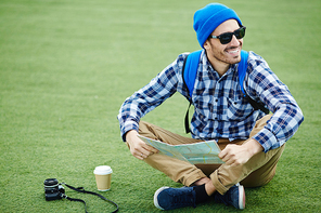 Man with map sitting on green lawn