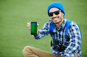 Happy traveler showing touchscreen of smartphone