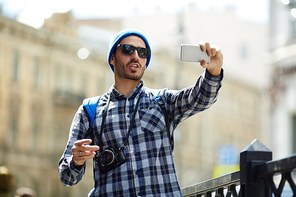 Young man making selfie while having walk in the city