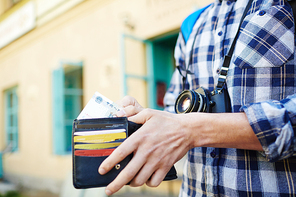 Closeup image of young tourist putting money in wallet, saving money  for vacation trips