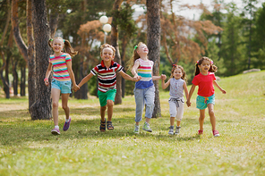 Happy children walking together in park and holding hands on a wonderful summer day