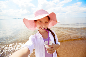 Happy girl in hat having drink on the beach