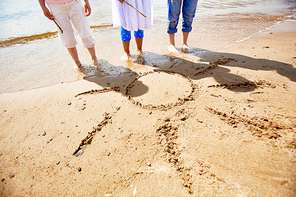 Legs of three girls standing on sand with picture of sun