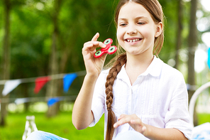 Pretty youngster playing with fidget spinner outdoors