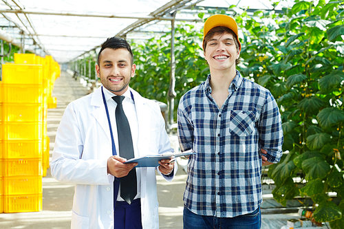 Group portrait of joyful young greenhouse workers  with wide smiles while distracted from quality inspection