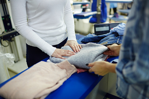 Dry-cleaning service worker giving clean folded pullover to client