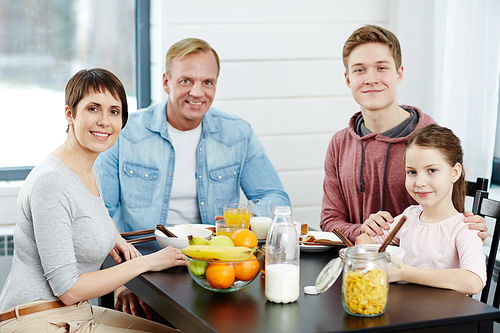 Healthy family members having breakfast by kitchen table