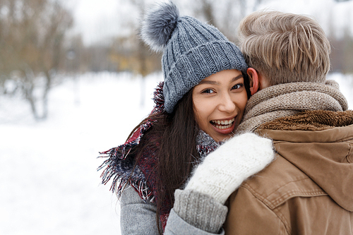 Happy girl in winterwear embracing her boyfriend