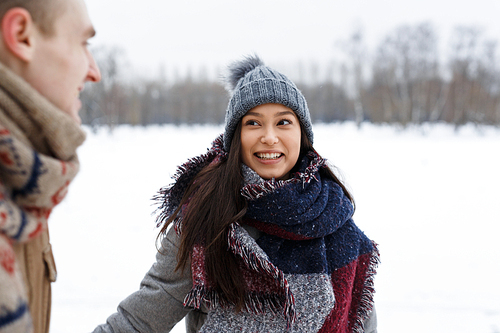 Happy girl in winterwear having walk with her boyfriend in winter