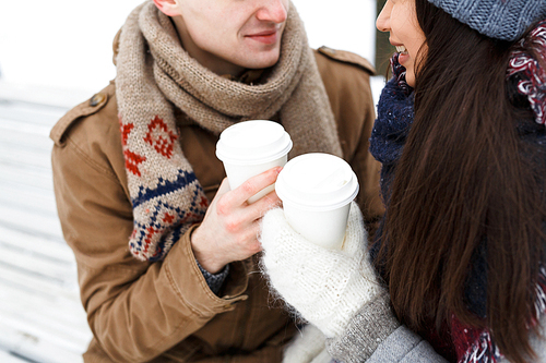 Plastic glasses with hot drinks in hands of amorous couple